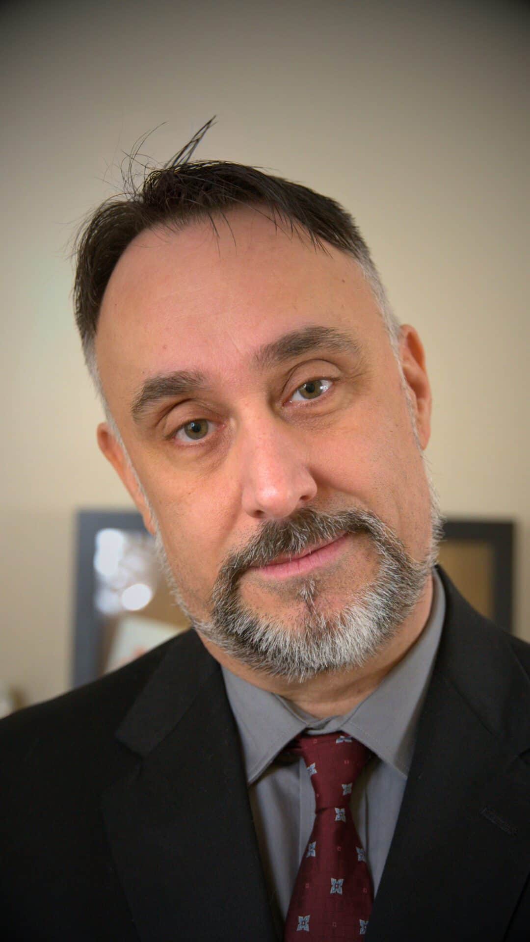 Professional headshot of Glenn Murano, founder of Southington Digital Solutions, wearing a black blazer, gray shirt, and patterned red tie, looking directly at the camera with a friendly expression.